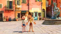 Deux jeunes garçons animés partageant un moment d'excitation dans un village italien vibrant, avec des bâtiments colorés et une fontaine fantaisiste en arrière-plan.