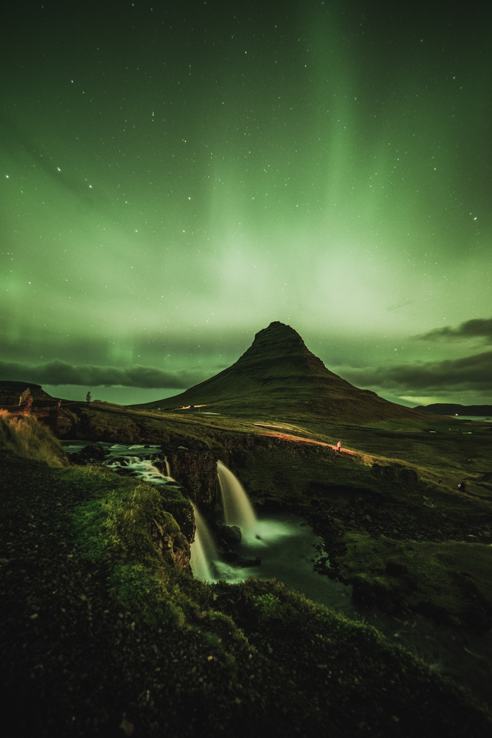 Arafed mountain with a waterfall and a green aurora light (aurora, cloud, atmosphere, ecoregion, natural landscape)