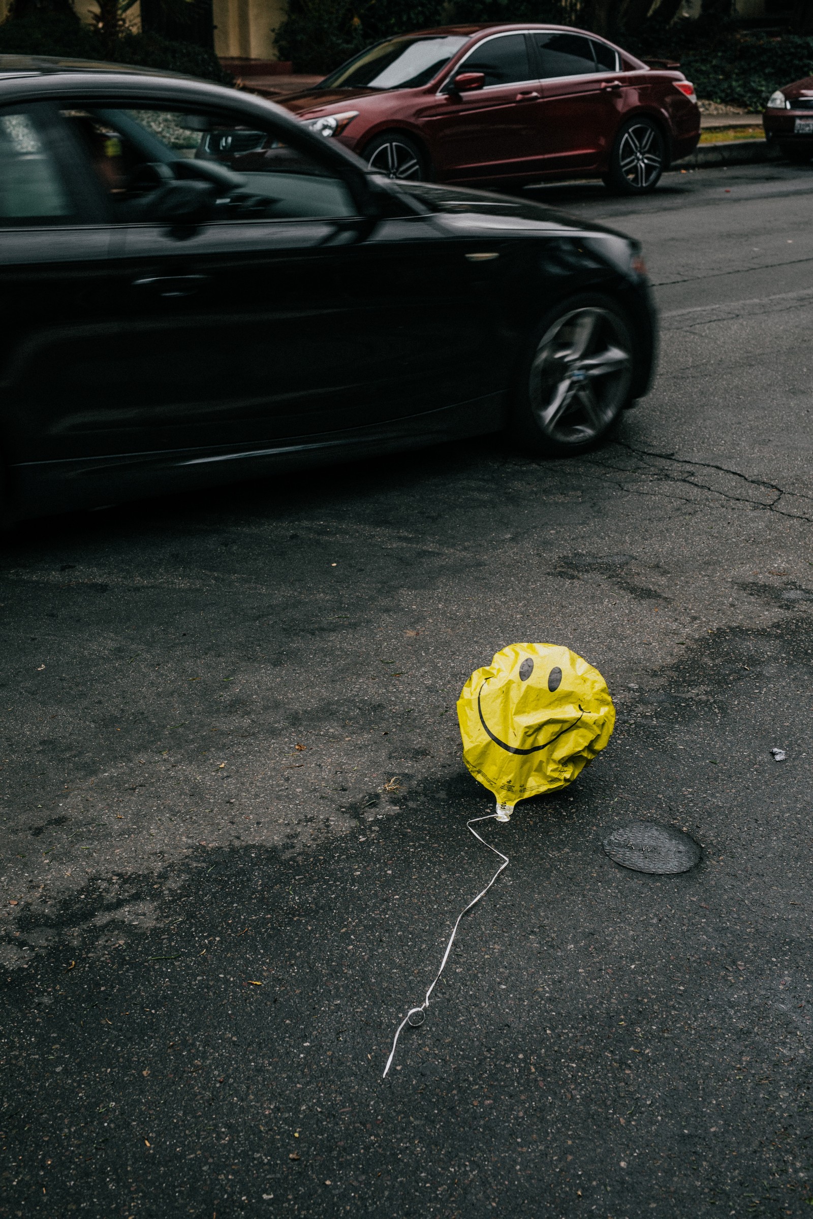 There is a yellow fire hydrant with a smiley face drawn on it (yellow, asphalt, road surface, road, wheel)