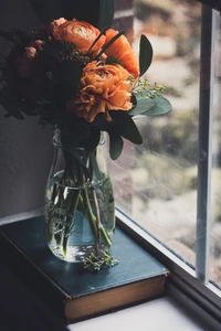 Ramo de flores vibrantes en un jarrón de vidrio junto a la ventana