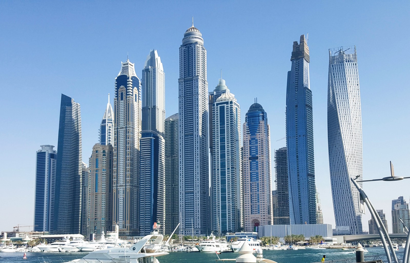 Os barcos estão atracados na água em frente a uma grande cidade (construção, edifício, arranha céus, cidade, bloco de torre)