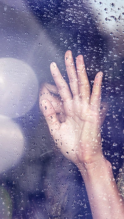 Girl's Hand Against Rain-Drenched Glass