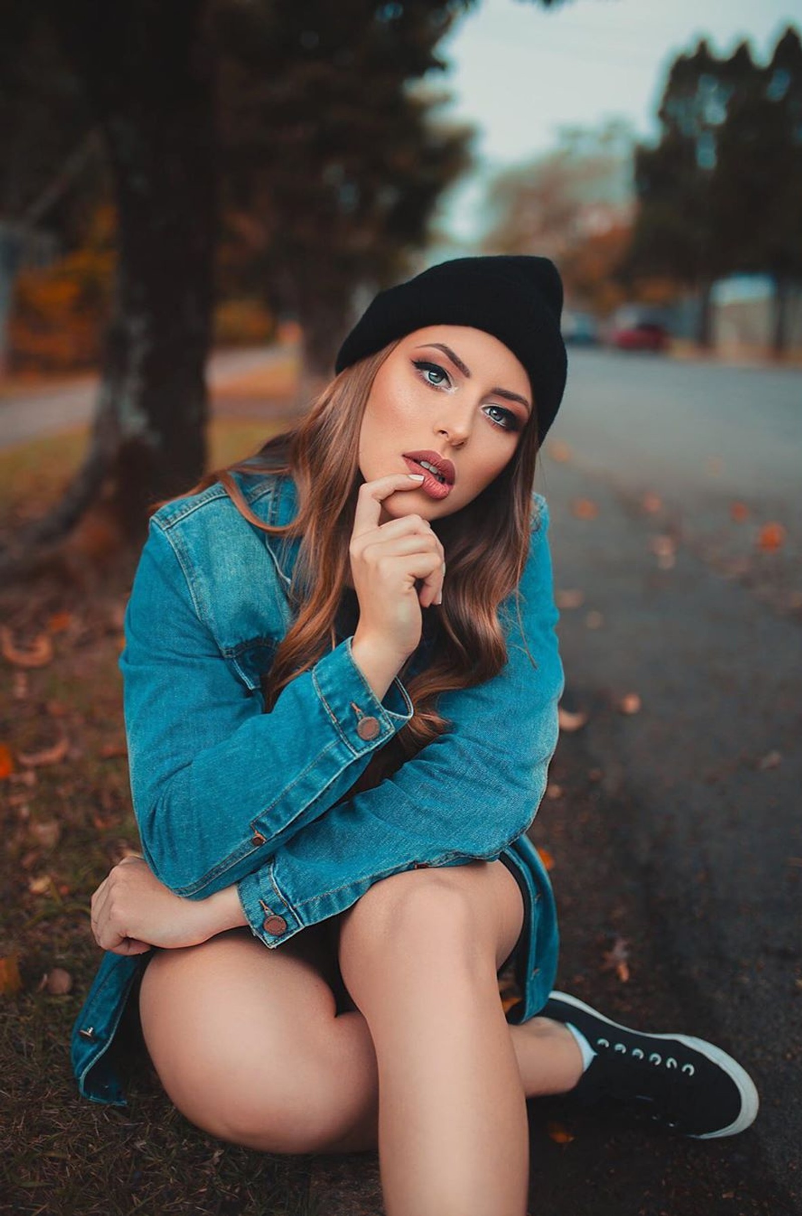 Arabische frau in einer jeansjacke und einem hut sitzt auf dem boden (mädchen, modell, stimmung, leute, fotografie)