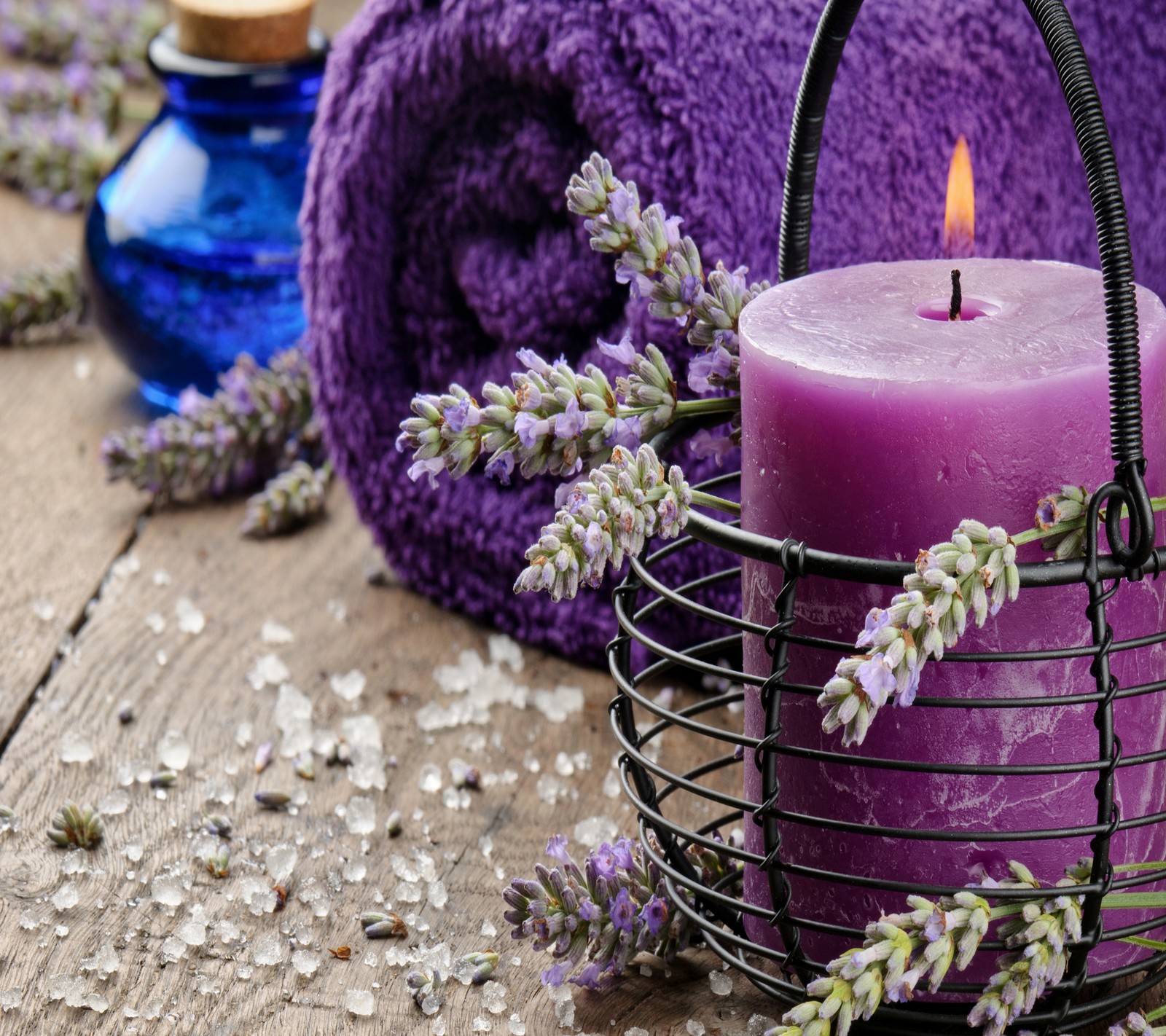 Flores de lavanda e uma vela estão colocadas em uma cesta sobre uma mesa. (spa, wellness)