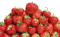 Fresh, ripe strawberries piled high, showcasing vibrant red color and lush green tops.