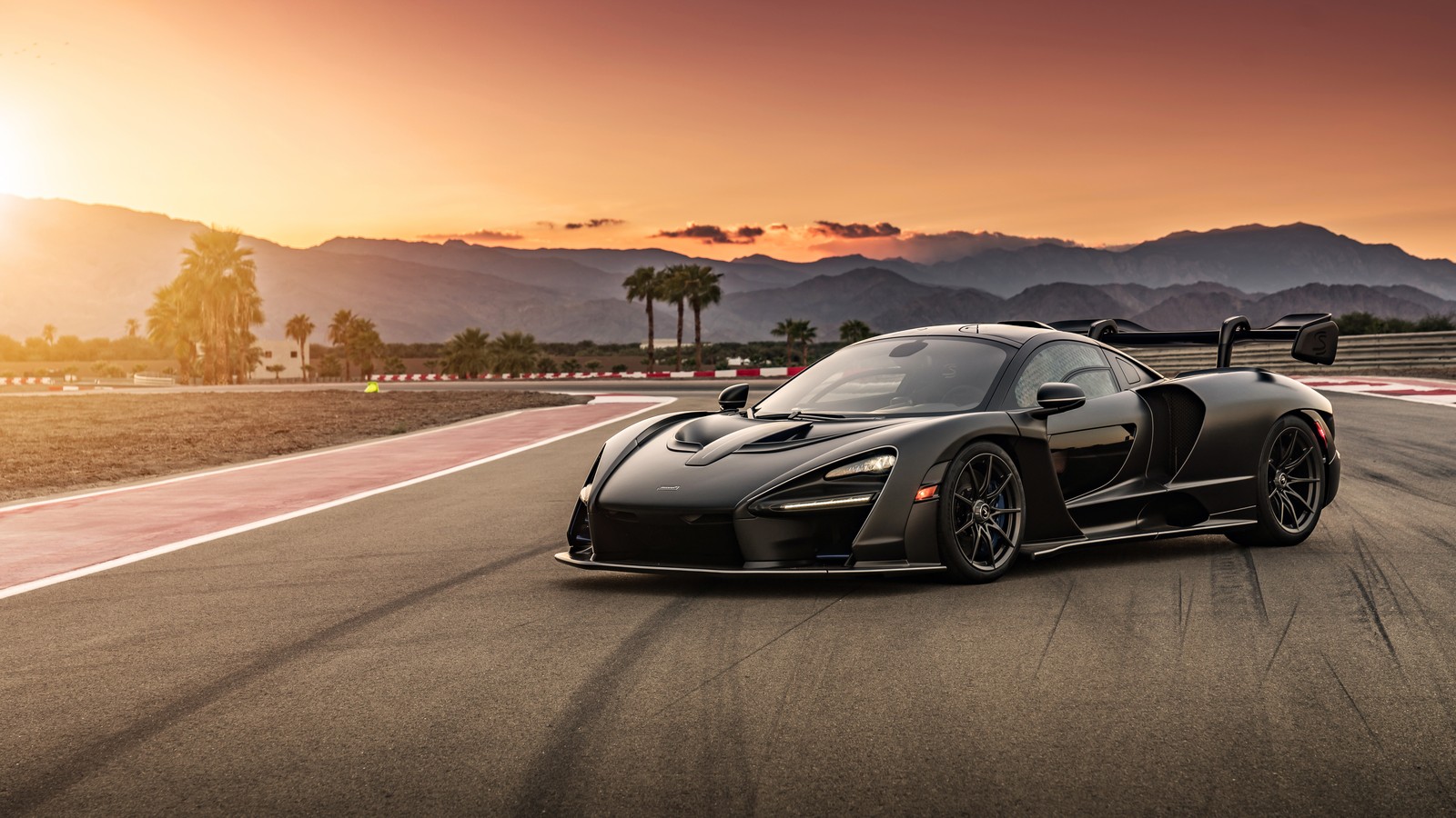 A black sports car driving on a track at sunset (mclaren automotive, mclaren, sports car, mclaren senna, car)