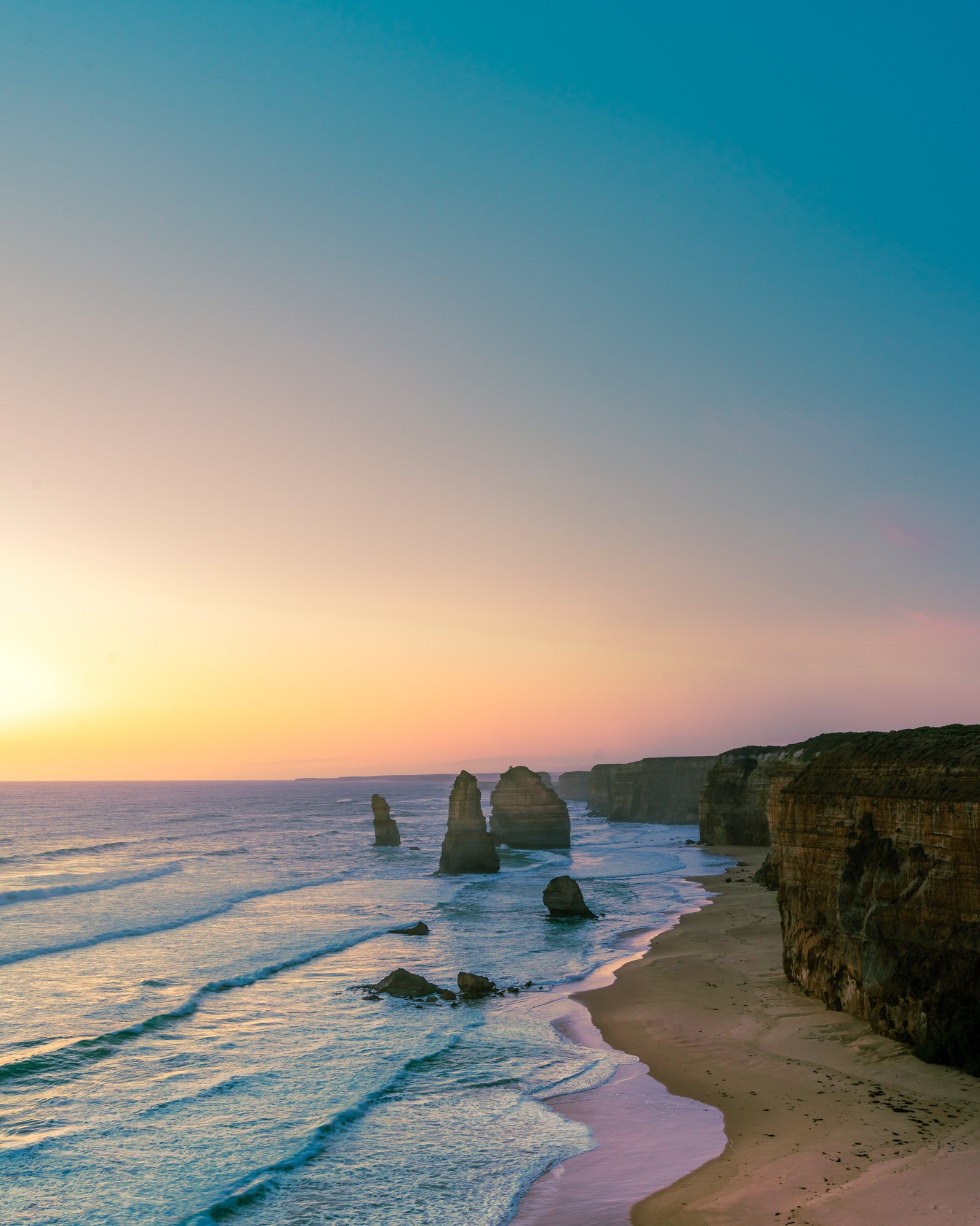 Coucher de soleil sur l'océan avec une plage et des falaises en arrière-plan. (voyage, eau, ressources en eau, écorégion, nuage)