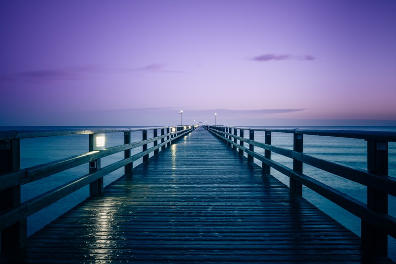 Вид на пирс с огнем на закате (prerow pier, германия, морской пейзаж, сумерки, фиолетовое небо)