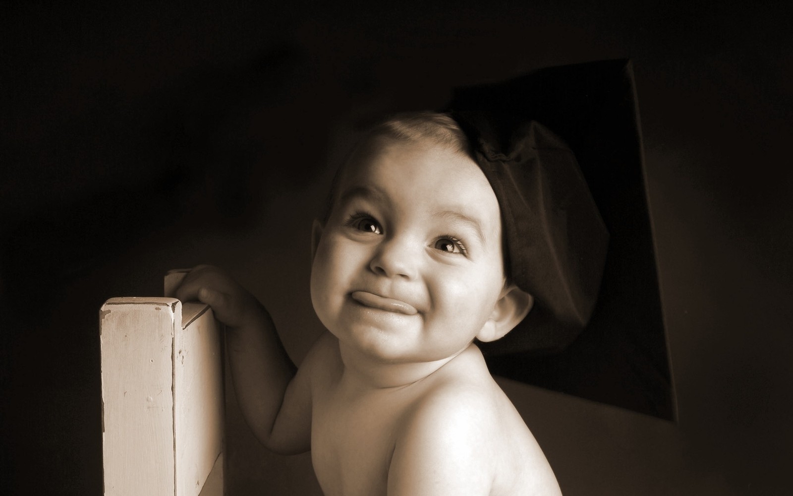 There is a baby that is sitting on a book (infant, cuteness, child, black, emotion)