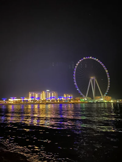 Dubai Nightscape: Reflections of the Ferris Wheel over Tranquil Waters