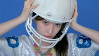 Wendy von Red Velvet in einem sportlichen Look mit einem weißen Helm vor einem lebhaften blauen Hintergrund.