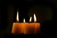 Illuminating Harmony: Four Candles Casting Warm Light in Darkness