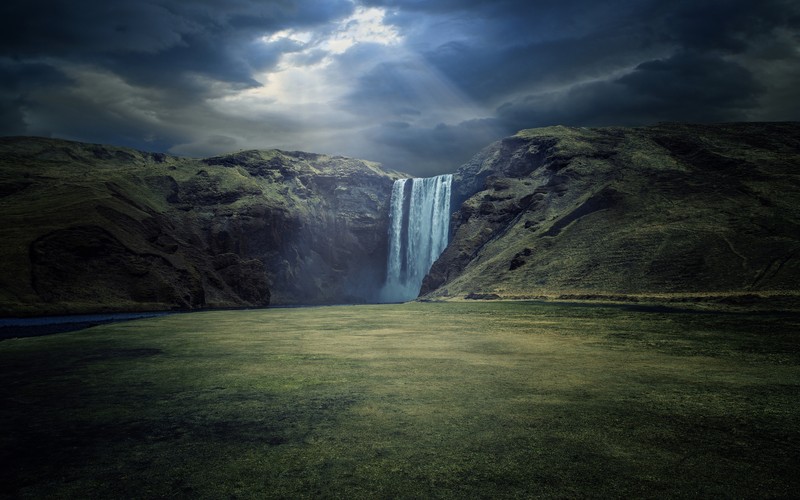 Большой водопад вытекает из зеленой долины (skógafoss, водопады, исландия, скалы, солнечные лучи)