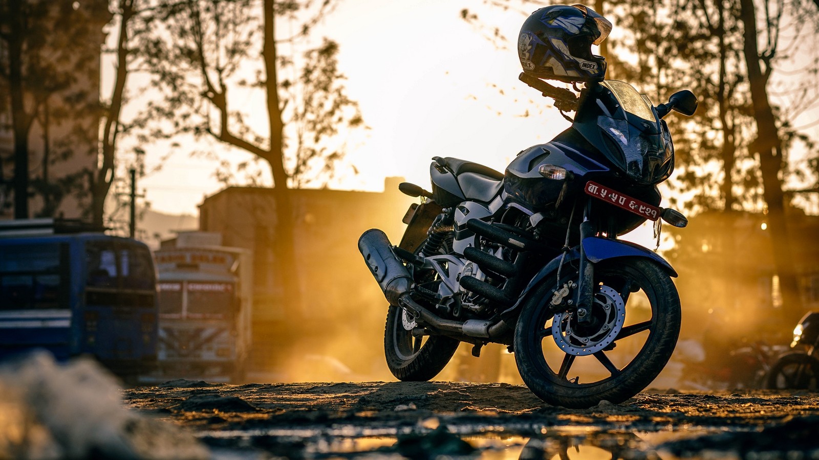 Uma motocicleta estacionada na terra com um capacete em cima (motocicleta, motociclismo, dublê, árvore, bokeh)