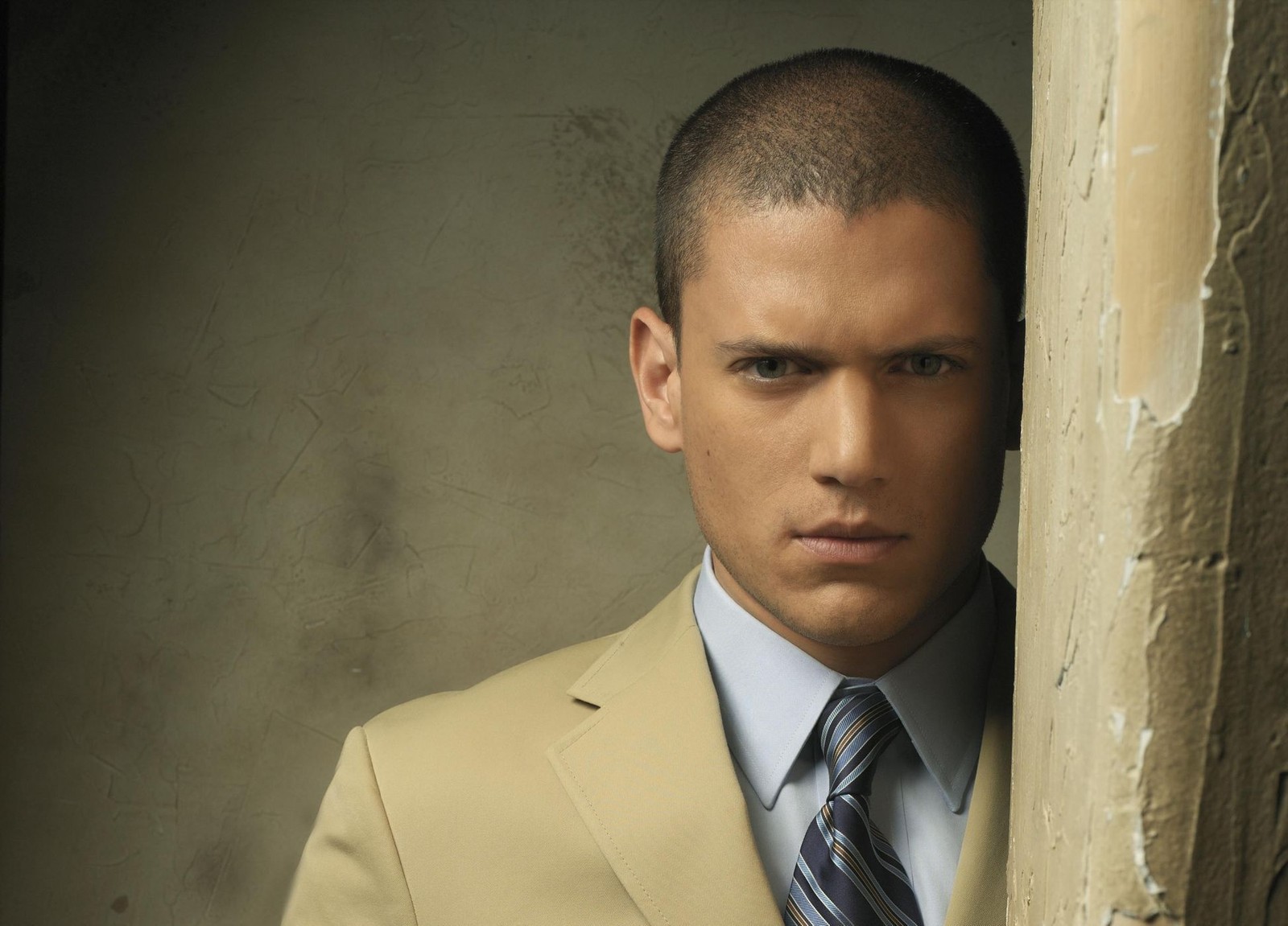 Un homme arabe en costume clair s'appuyant contre un mur (wentworth miller, costume, front, employé de bureau, émission de télévision)