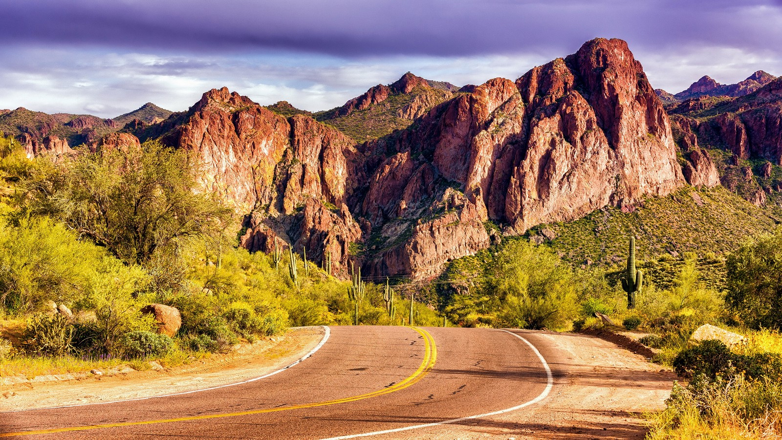 Una vista de una carretera sinuosa en el desierto con montañas al fondo (formas montañosas, naturaleza, badlands, camino, montaña)