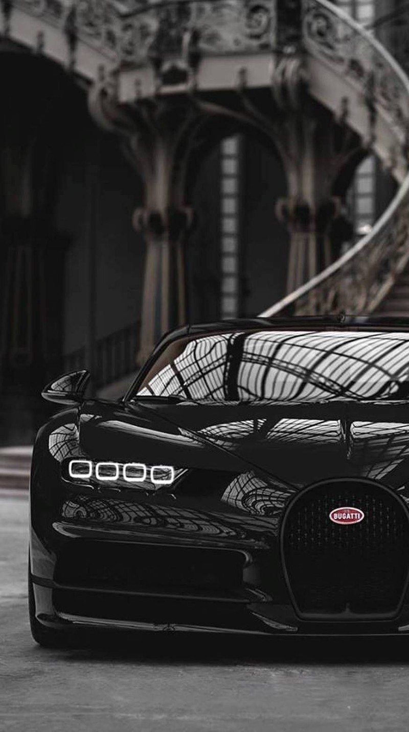 Un gros plan d'une voiture bugatti noire garée devant un bâtiment (voiture, sport)