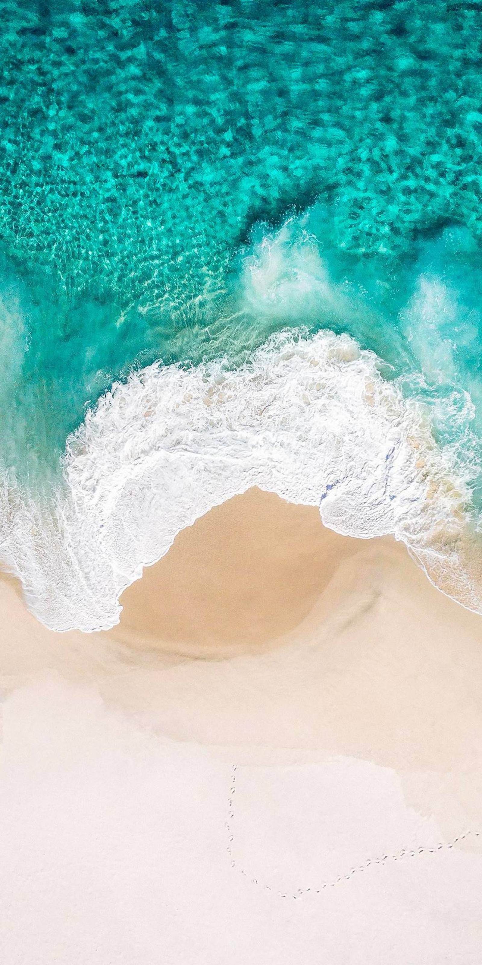 Aerial view of a beach with a wave crashing on the sand (apple, beach, ios, iphone, nature)