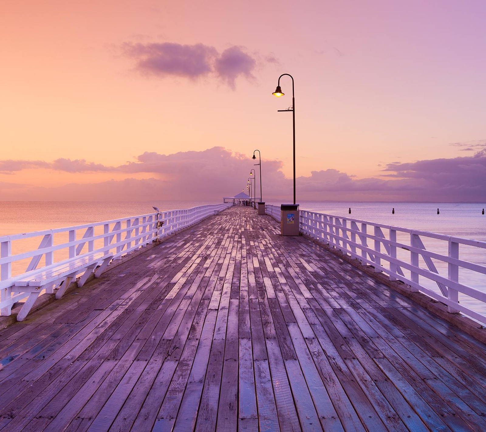 Um pier de madeira com um banco e luzes de rua nele (bonito, ponte, água)