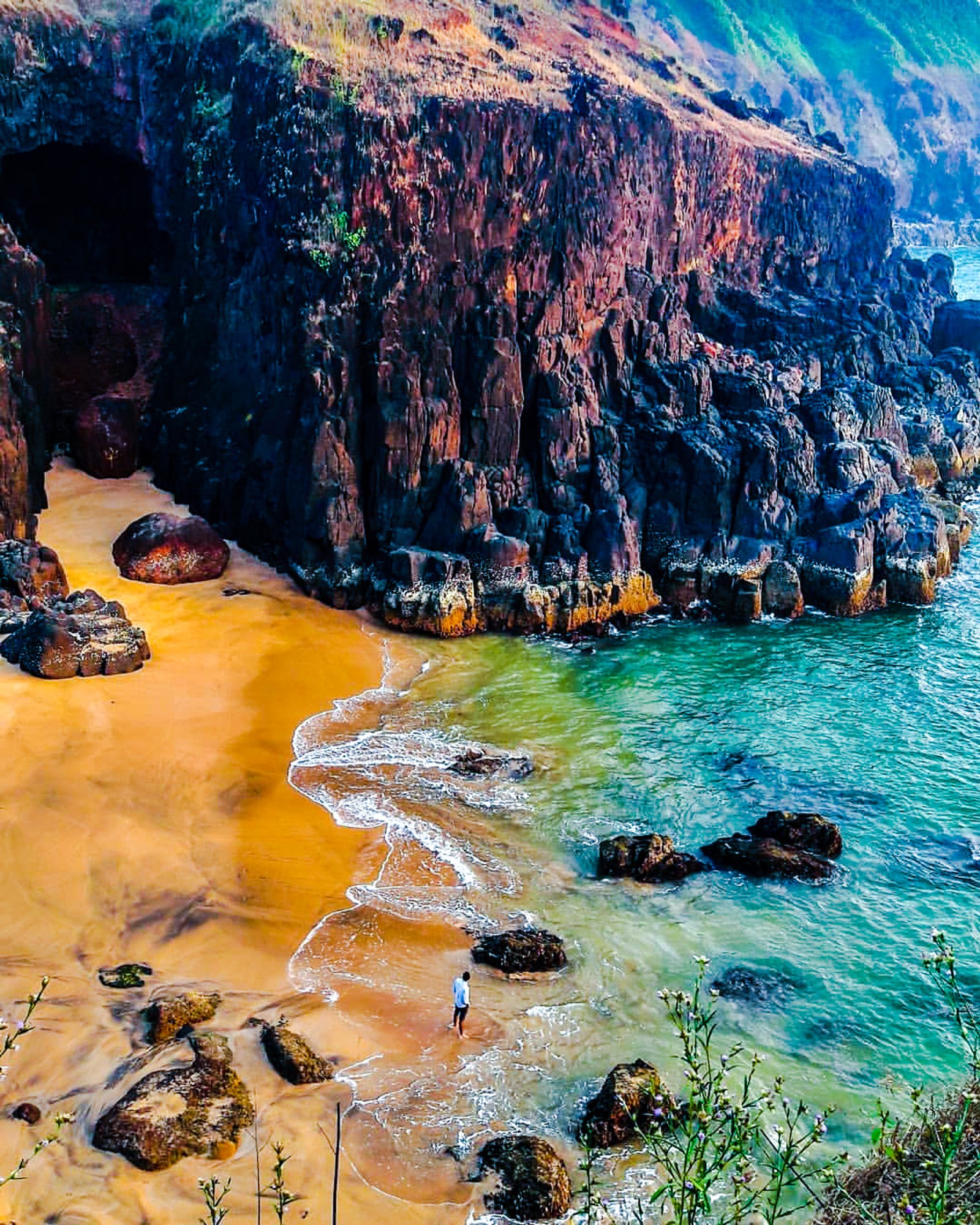 There is a person walking on the beach near the water (sea, beach, mountain, alone, boy)