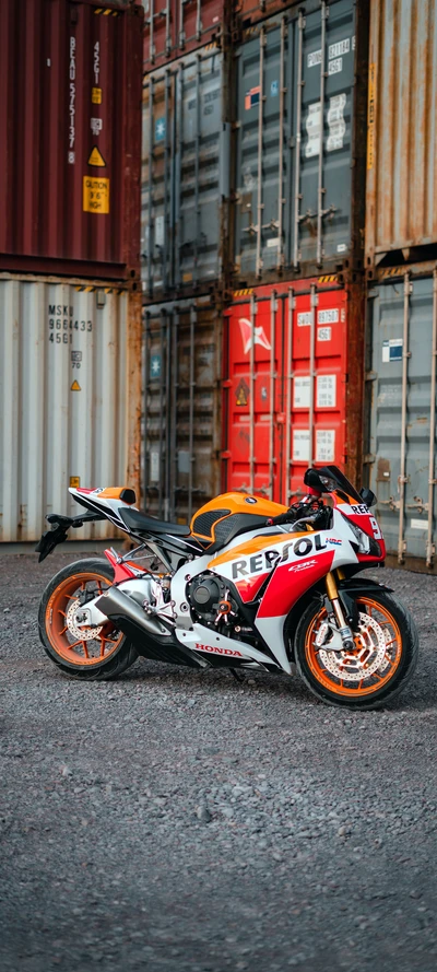 Motocicleta Honda con librea Repsol contra fondo industrial