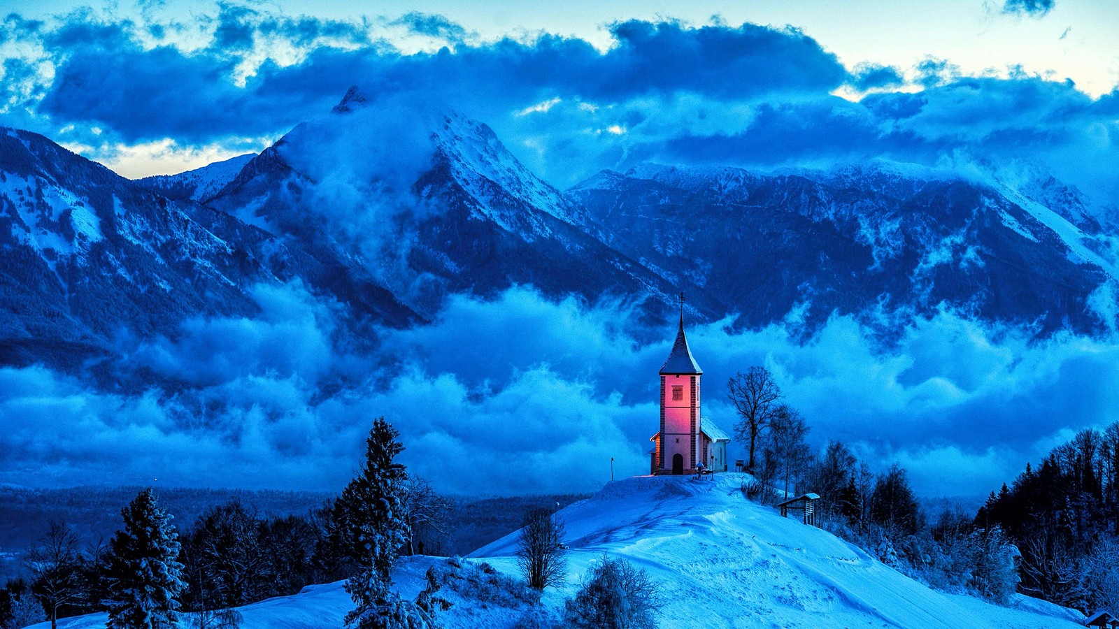 Una vista de una iglesia en medio de una montaña nevada (nube, atmósfera, montaña, nieve, azul)