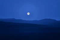 Pleine lune illuminant le paysage montagneux bleu serein