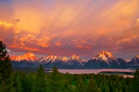 Majestätischer Sonnenaufgang über den Grand-Teton-Bergen, der die Gipfel erleuchtet und sich im ruhigen See darunter spiegelt.