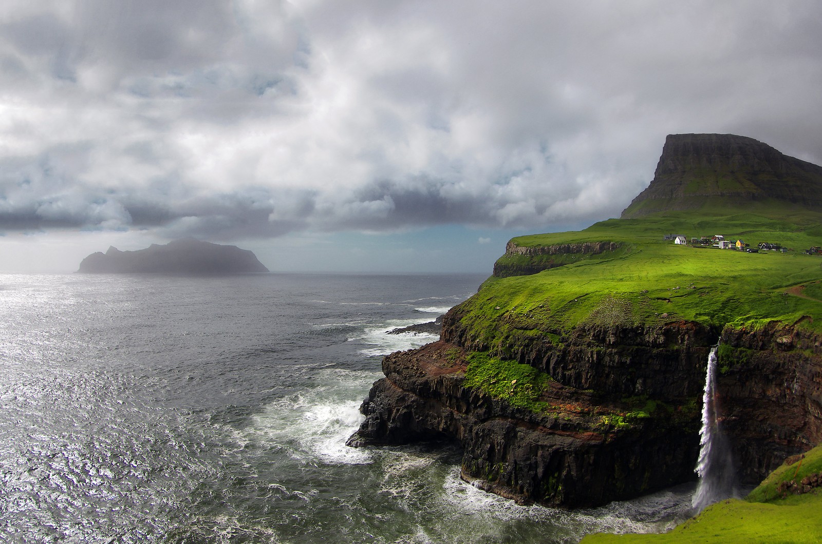 Arafed view of a waterfall on a cliff with a green field and a small house (nature, coast, cliff, sea, headland)