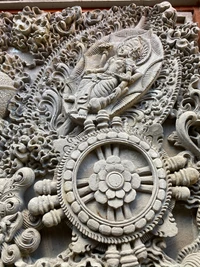 Intricate Balinese stone relief depicting a mythological figure, showcasing elaborate patterns and symmetrical designs in creative artistry.