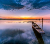 Réflexion sereine du coucher de soleil sur des eaux calmes avec un bateau solitaire