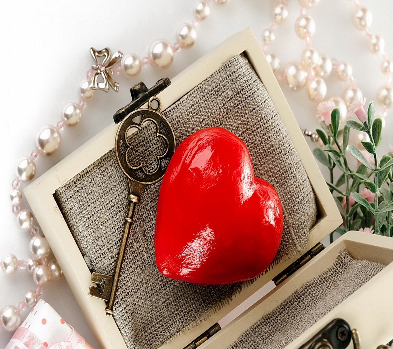 Hay un objeto en forma de corazón en una caja roja con una llave (corazón, llave, amor, romántico)