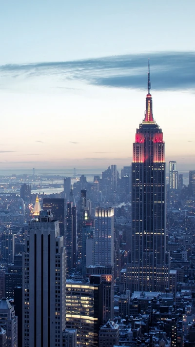 Stunning skyline featuring the iconic Empire State Building illuminated at dusk among towering city structures.