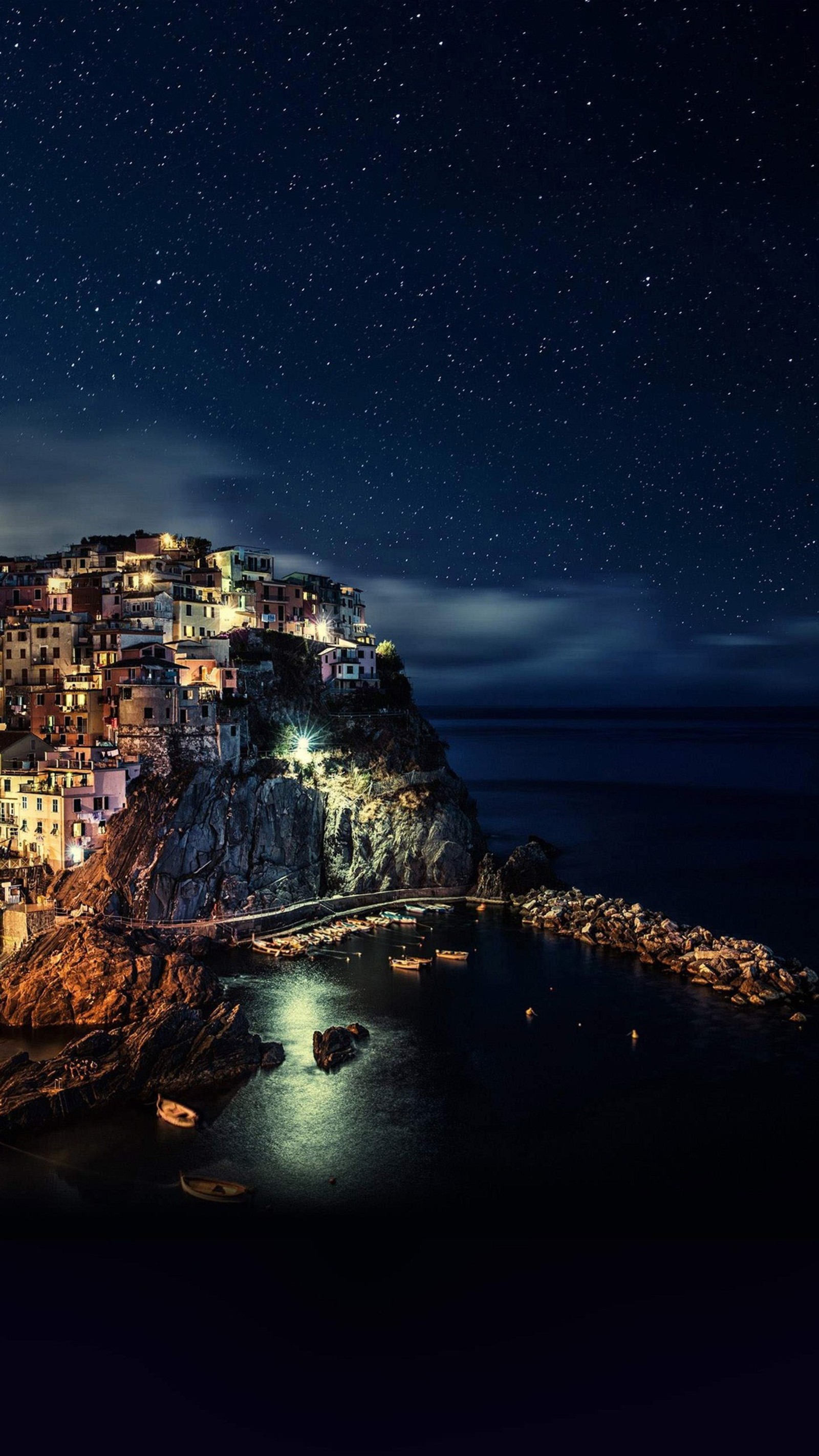 Night time view of a town on a cliff overlooking the ocean (best, black, hdr, uhd, wallpaper)