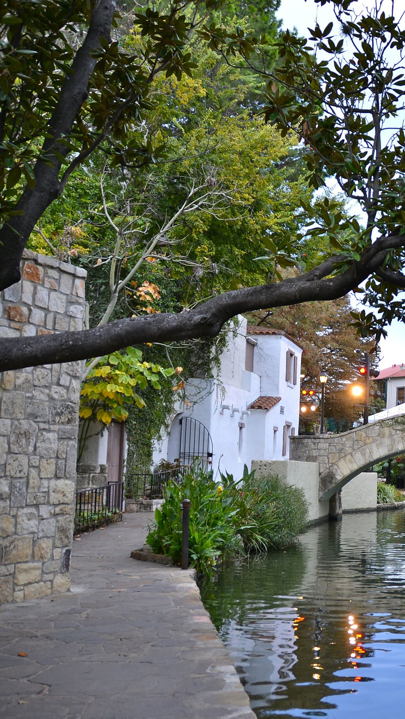 Un puente sobre un río con un edificio al fondo (paseo del río, san antonio)