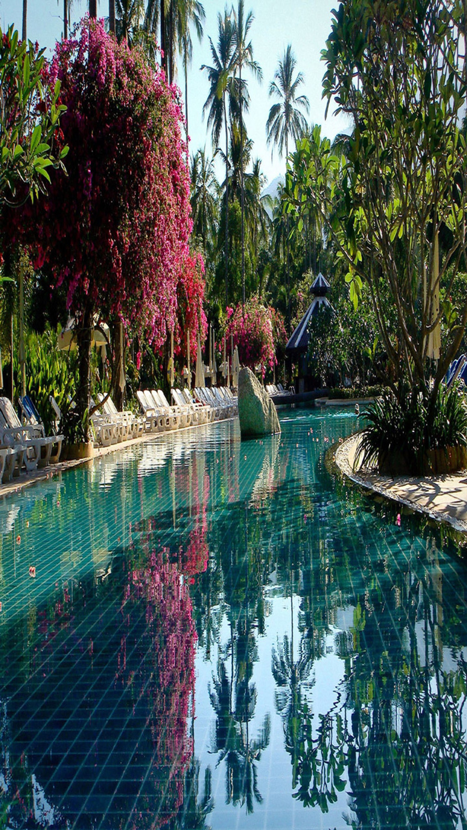 There is a pool with a waterfall and a gazebo in the background (beautiful, cute, look, nice)