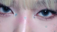 Gros plan enchanteur des yeux scintillants de Ningning, ornés de maquillage scintillant et de délicates embellissements, capturant l'essence de l'art du K-pop.