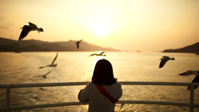 Girl Watching Seabirds at Sunrise Over Calm Waters