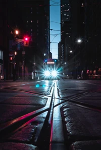 Urban Nightscape: Illuminated Car Headlamps on Gleaming Tracks