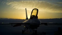 Silhouette of a military fighter jet against a dramatic sunset sky.