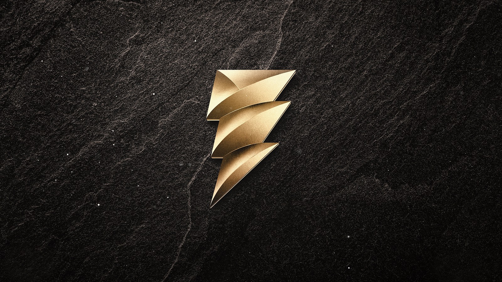 Un primer plano de un broche dorado sobre una superficie negra (shazam 2019, película, logotipo)