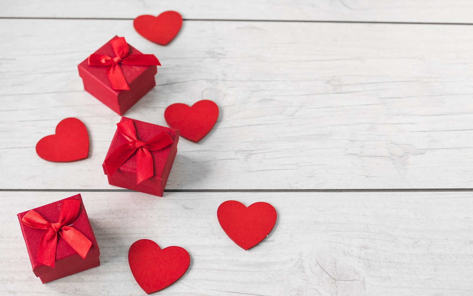 Boîtes-cadeaux rouges avec des cœurs sur un fond en bois blanc (saint valentin, cœur, rouge, pétale, amour)