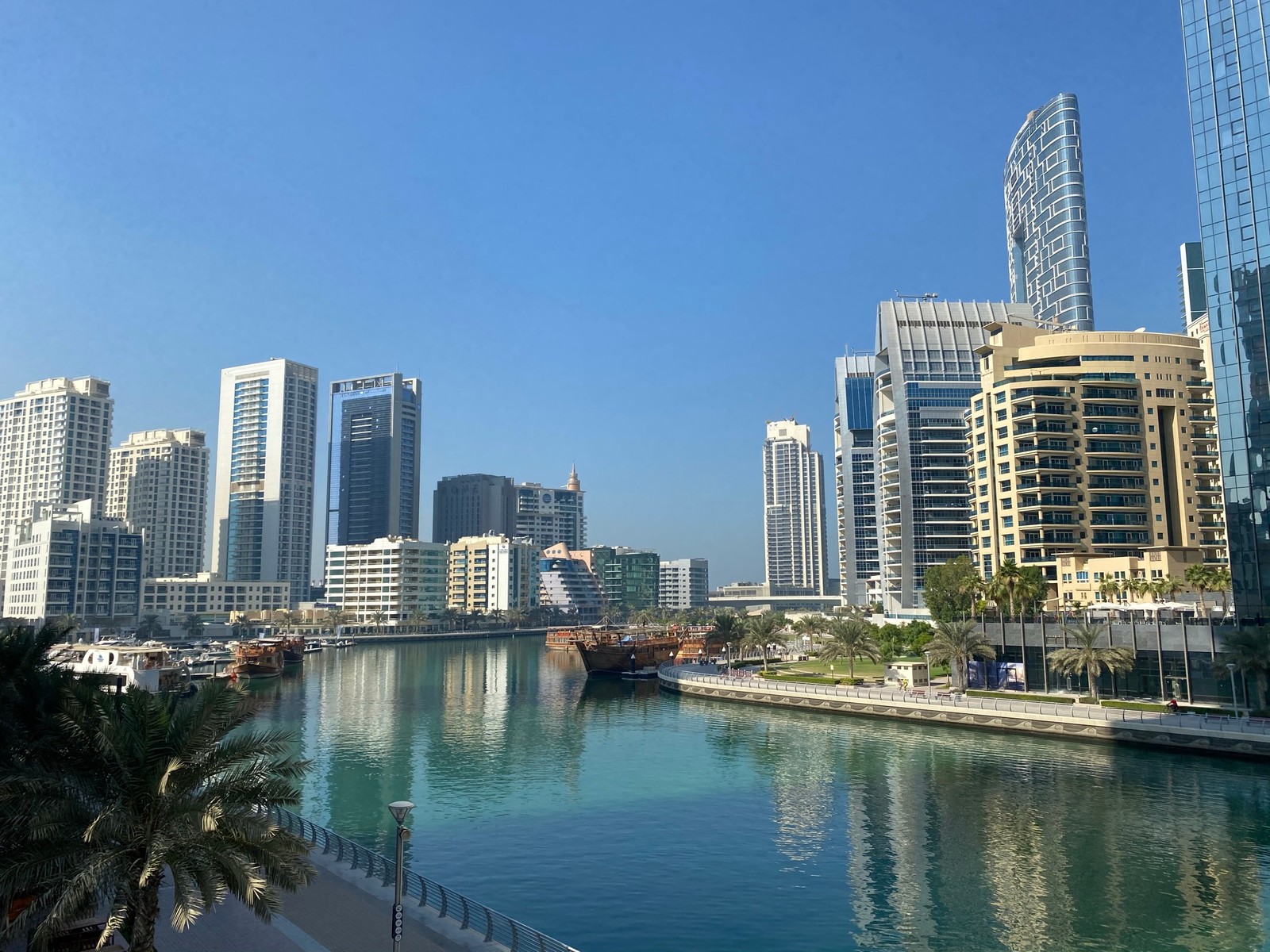 Vista aérea de uma cidade com um rio e um barco na água (dubai, marina de dubai, corpo de água, bloco de torre, dia)