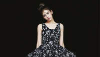 Jeon Somi en un vestido negro floral contra un fondo oscuro