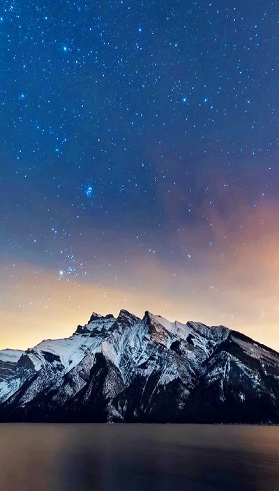 Snow-capped mountains under a starry night sky.