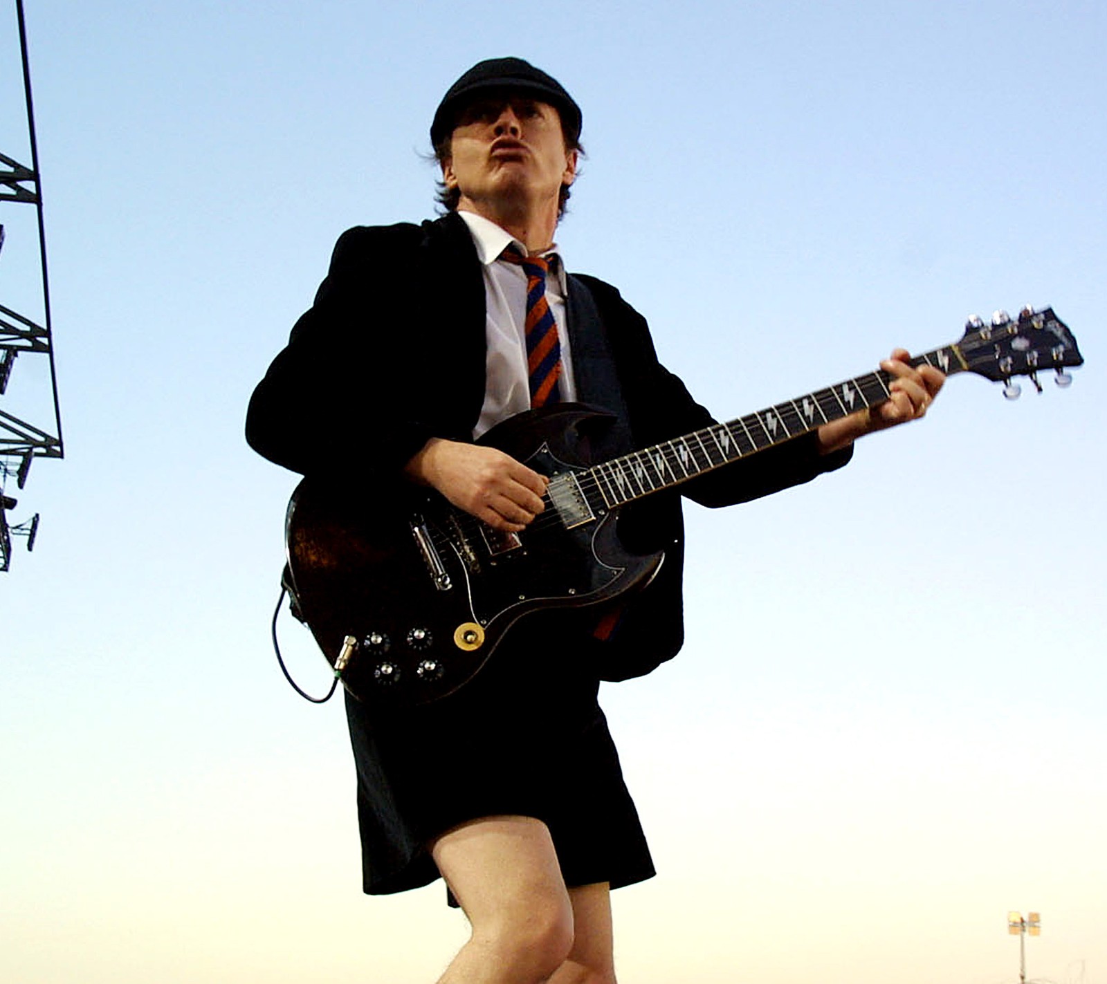 Hay un hombre en traje y corbata tocando la guitarra (acdc, vivir)