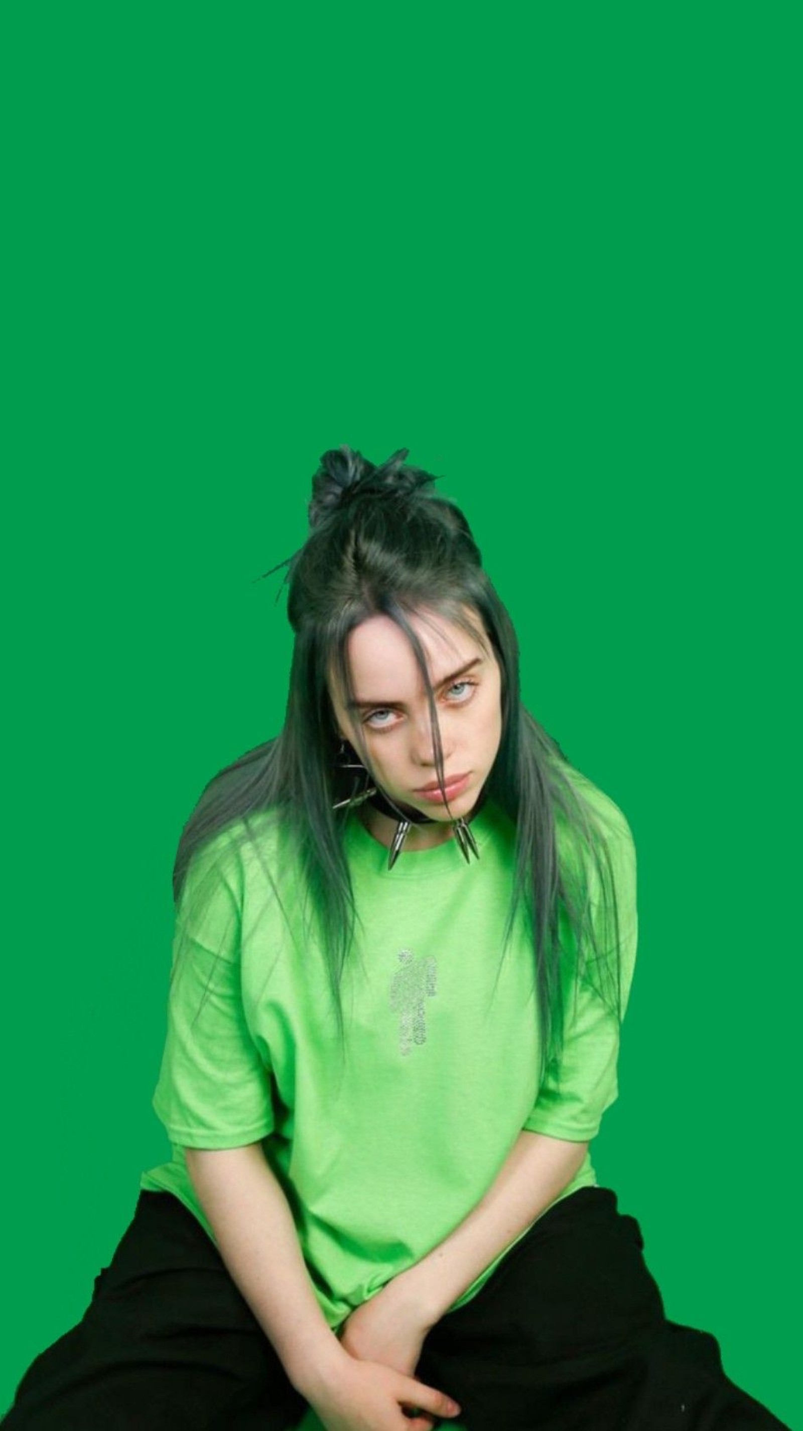 Arabische frau mit grünem shirt sitzt auf einem hocker mit den händen auf dem bauch (billie eilish, sänger)