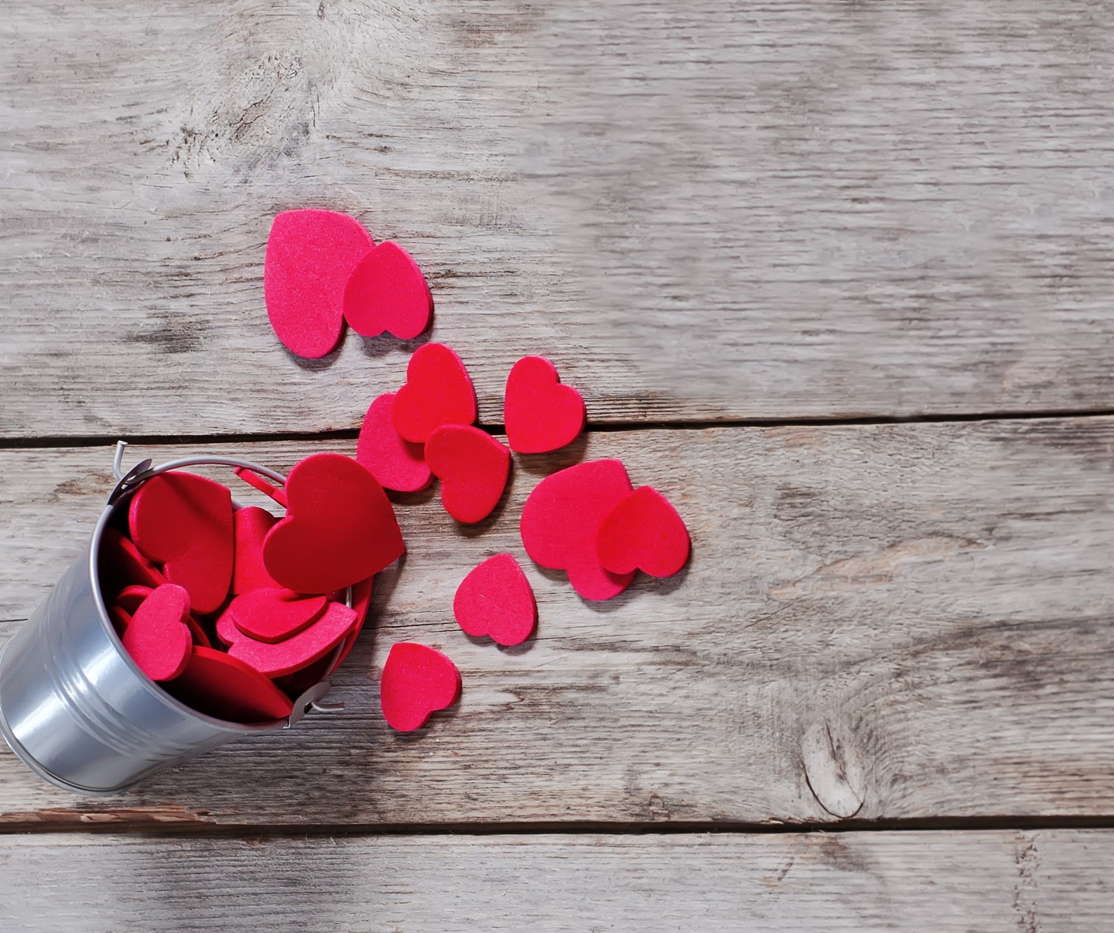 There is a bucket of hearts on a wooden table (heart, love)