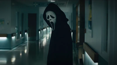 Ghostface schleicht in einem schwach beleuchteten Krankenhausflur.