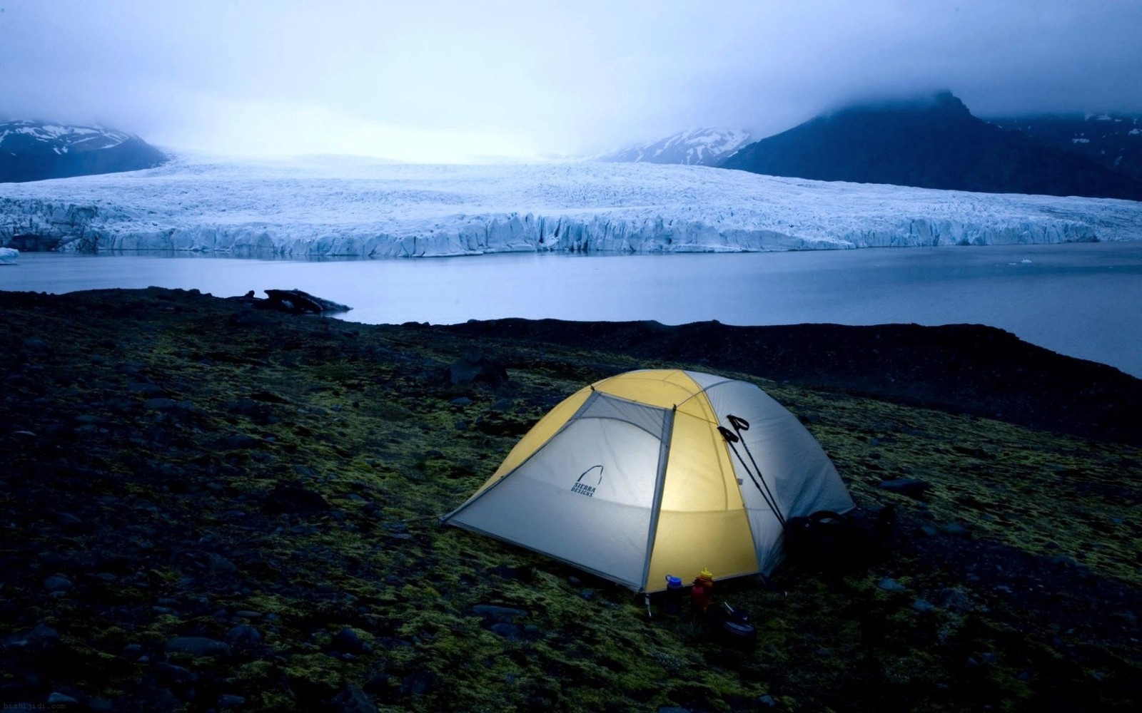 Arafed tent pitched up on a grassy hill overlooking a glacier (camping, campsite, wilderness, mountain, fell)